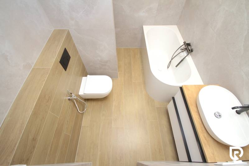 A family house bathroom with a bathtub, toilet, and floor with a wood decor.