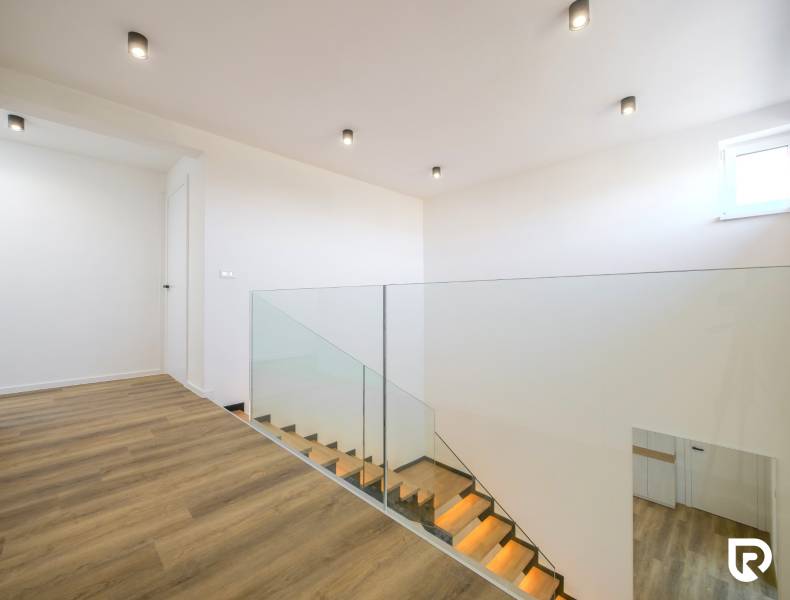 A family house with a staircase and a wooden decor floor, ceiling lights.