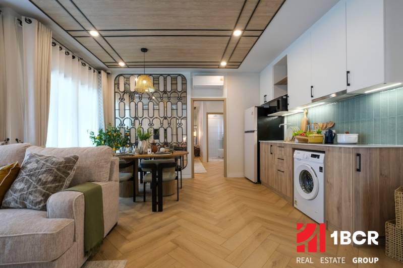 Interior of a 3-room apartment with a kitchen, dining table, and wooden decor flooring.