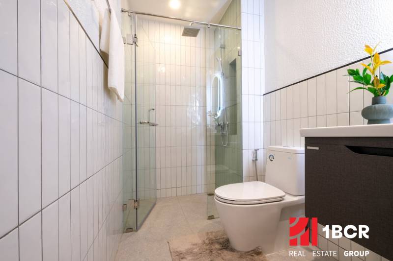 A bathroom in a 3-room apartment with a modern shower, toilet, and decorative tiling.