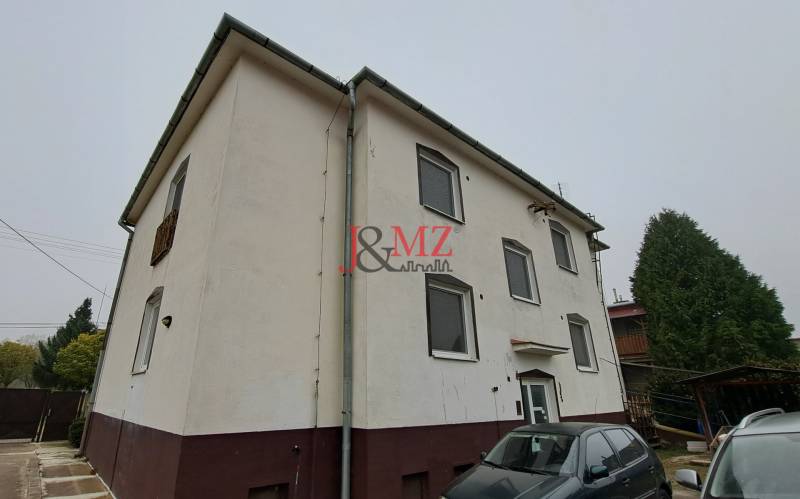 A family house in Kalná nad Hronom with parked cars and a coniferous tree in the yard.
