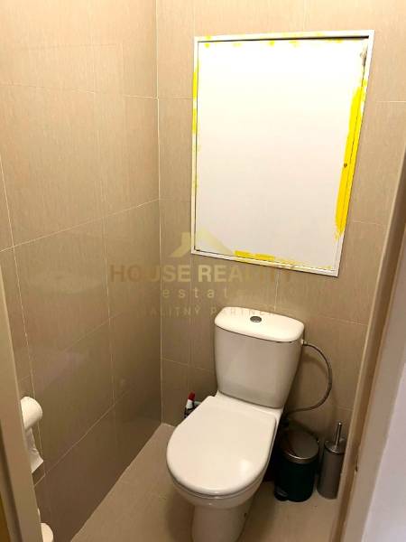 A toilet with tiled walls and a mirror in a 3-room apartment.