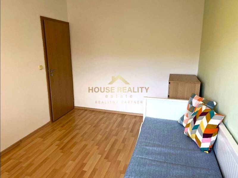 A room in a 3-bedroom apartment with a bed and decorative pillows, wooden decor flooring.