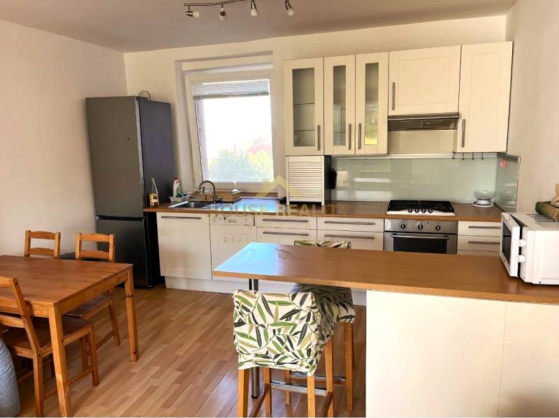 A kitchen in a 3-room apartment with a wooden floor decor and a dining table.
