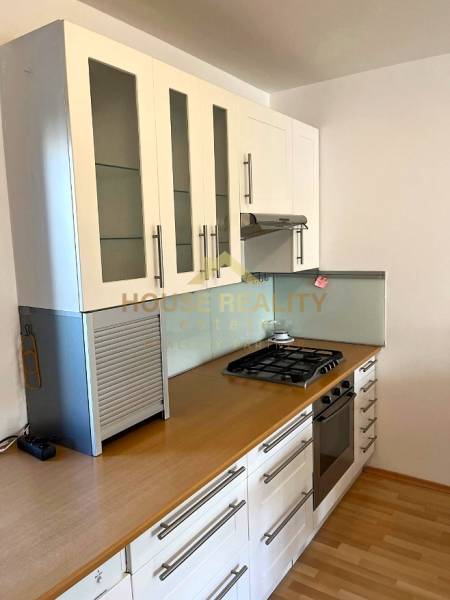 A kitchen in a 3-room apartment with a gas stove and a floor with a wooden decor.