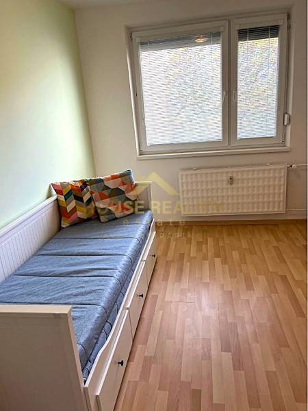 A room in a 3-room apartment with a bed, colorful pillows, and a floor with a wooden decor.