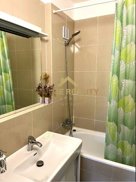 A bathroom in a 3-room apartment with a bathtub, shower, and green curtain.