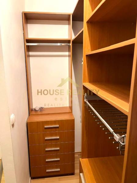 A wardrobe with shelves and drawers in a 3-room apartment, flooring with a wood decor.