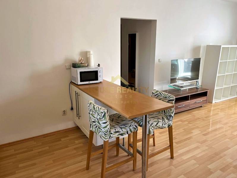 Dining counter in a 3-room apartment with a wooden decor floor and a television.