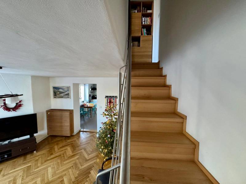 A staircase in a 3-room apartment with a wooden decor floor and a Christmas tree.