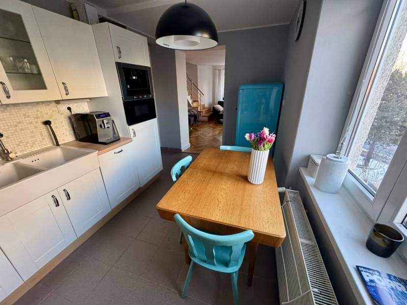 A kitchen in a 3-room apartment with a white kitchen unit, a wooden table, and a turquoise refrigerator.