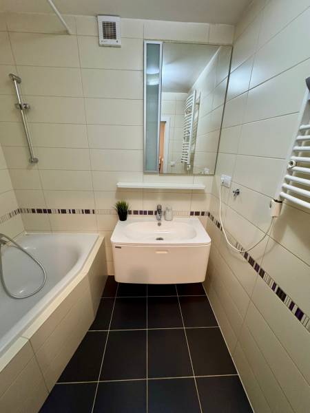 Bathroom in a 3-room apartment with a bathtub, tiled walls, and a sink.