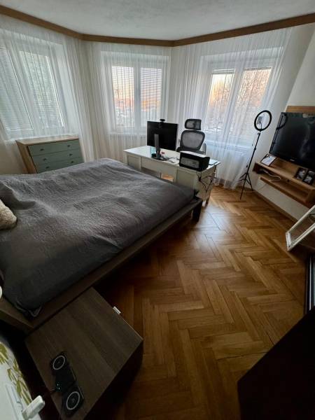 Bedroom in a 3-room apartment with wood-patterned flooring, a work corner, and a TV.