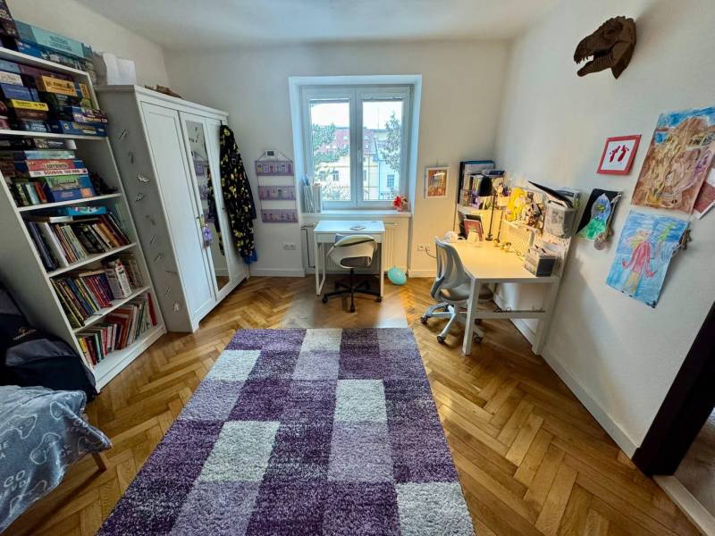 Children's room in a three-room apartment with a wooden decor floor and a desk.