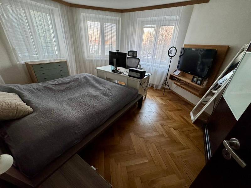A bedroom in a 3-room apartment with a television and a floor with a wooden decor.
