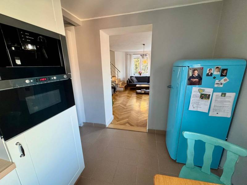 A kitchen with a retro refrigerator, a view of the living room, and a wooden decor floor in a 3-room apartment.