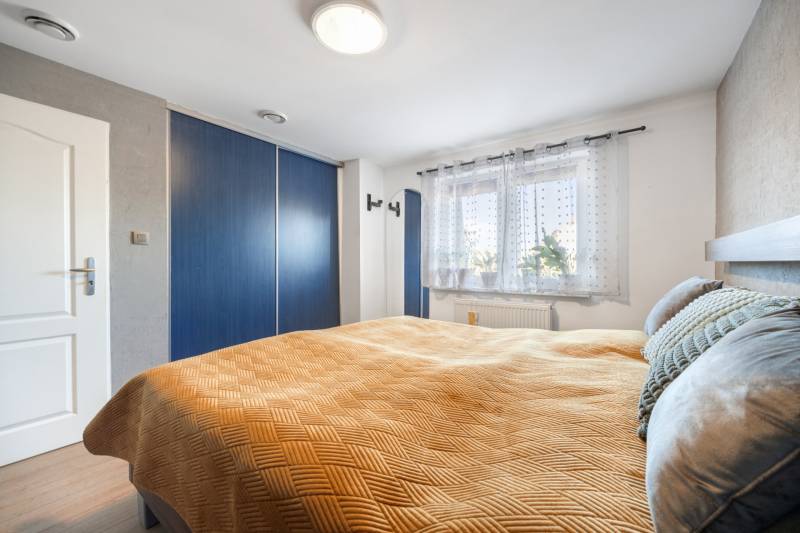 Bedroom in a family house with a built-in wardrobe and a window with plants.