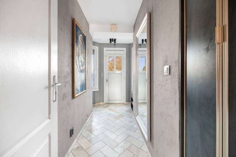 A hallway in a family house with a painting, a mirror, and ceramic tiles.