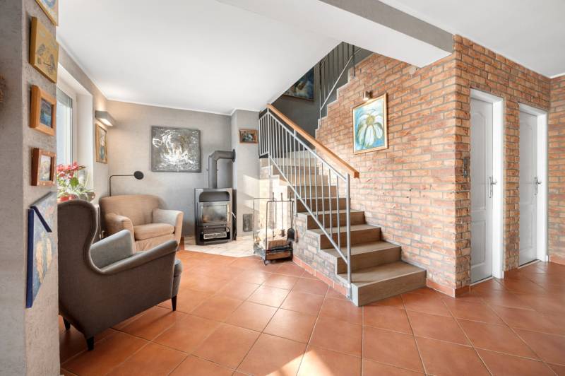 Living room in a family house with a brick wall, staircase, and fireplace.