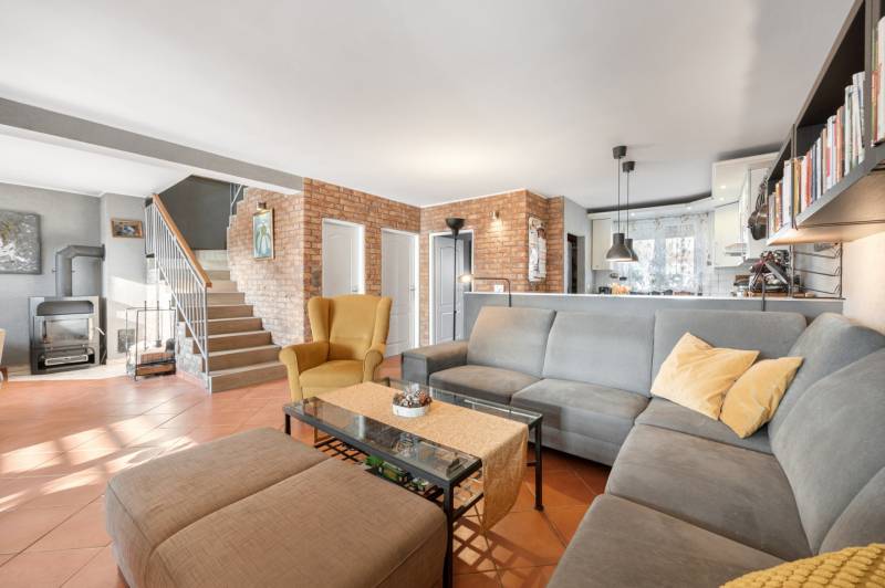 Living room with a brick wall, furniture, and a fireplace in a family house. Rustic interior with a carpet.