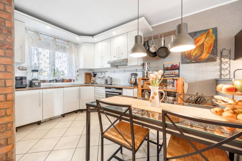 A kitchen in a family house with white cabinets, a glass table, and decorative accessories.