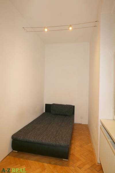 A room with a bed and a wooden decor floor in a 3-room apartment.