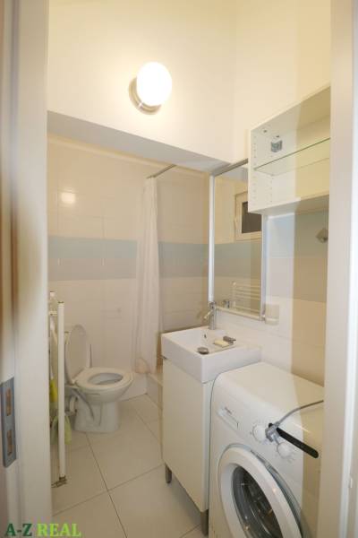 Bathroom with a washing machine, toilet, and shower in a 3-room apartment.