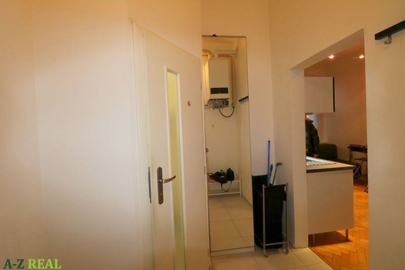 A hallway in a 3-room apartment with tiles and a view into the living room.