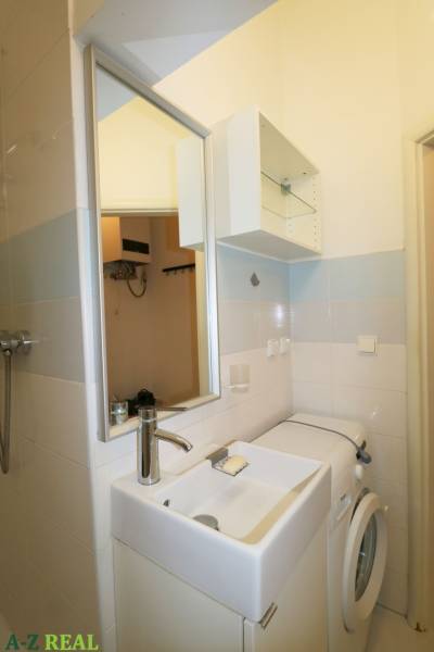 A bathroom with a sink, mirror, and washing machine, suitable for a 3-room apartment.