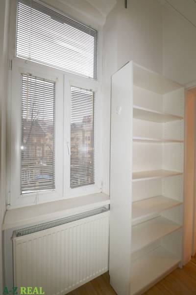 White shelf, radiator, and window with blinds in a 3-room apartment.