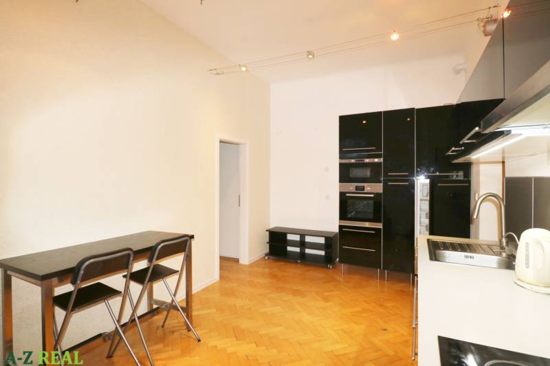 A kitchen in a 3-room apartment with a kitchen unit, table, and floor with a wooden decor.