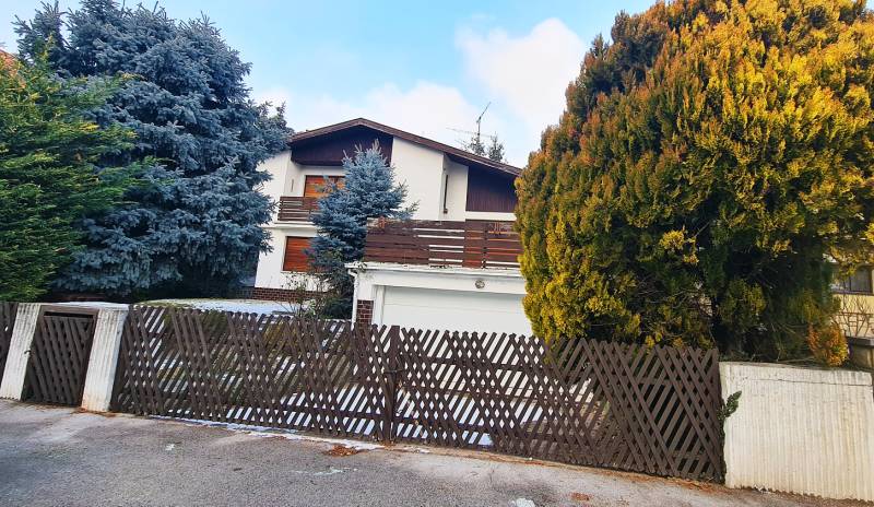 A family house on Fibichova Street in Bratislava - Ružinov surrounded by trees and a fence.