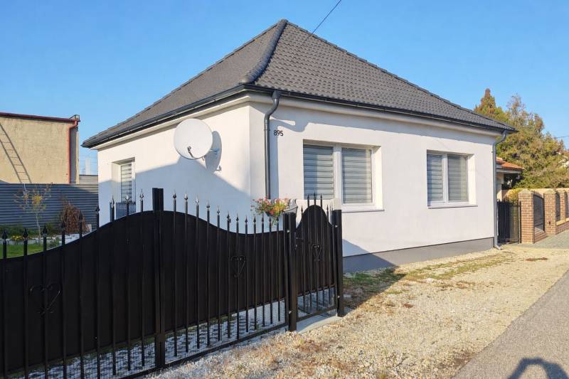 A family house in Horné Saliby with a white facade, a black roof, and a satellite dish.