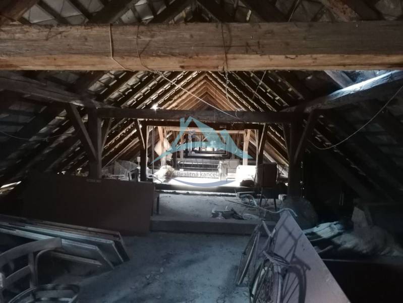 Attic of a family house with an old wooden beam roof structure, a room full of objects.