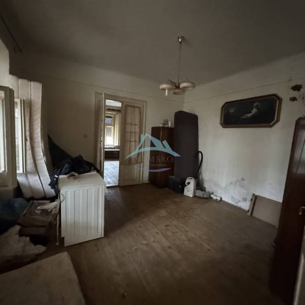 A room in a family house with a wooden decor floor, older furniture, and decorative paintings.