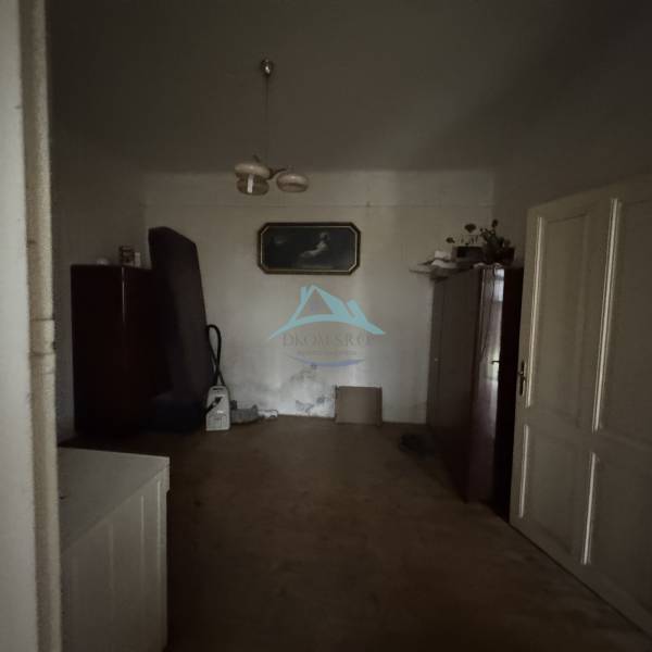 A room in a family house with wooden decor flooring, simple decorations, and furniture.