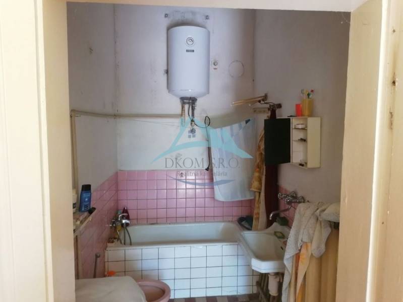 A bathroom in a family house with pink tiles and a boiler above the bathtub.