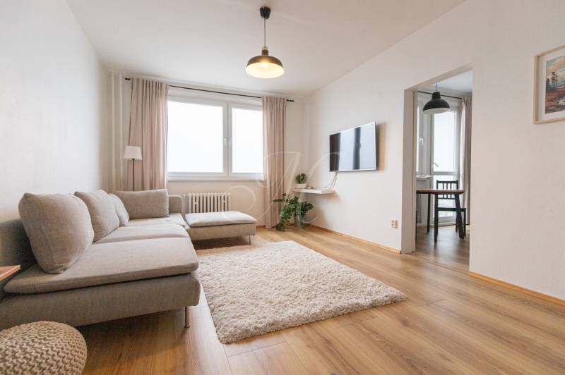 Living room with a sofa, TV, carpet, and wood-patterned flooring in a 3-room apartment.