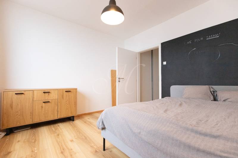 A bedroom in a 3-room apartment with a wooden decor floor, a comfortable bed, and a dresser.