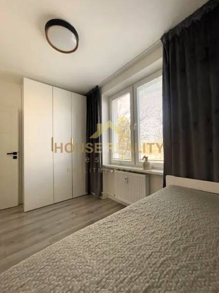 Bedroom in a 3-room apartment, wooden decor flooring, large window with curtain.