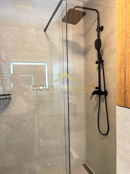 A shower enclosure with glass doors and a black showerhead in a 3-room apartment.