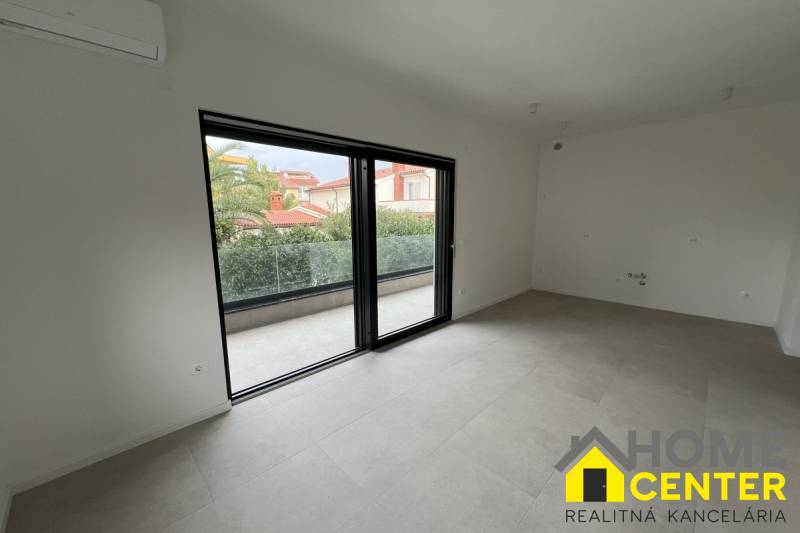 Spacious interior of a holiday apartment with a balcony, large glass doors, and tiled flooring.