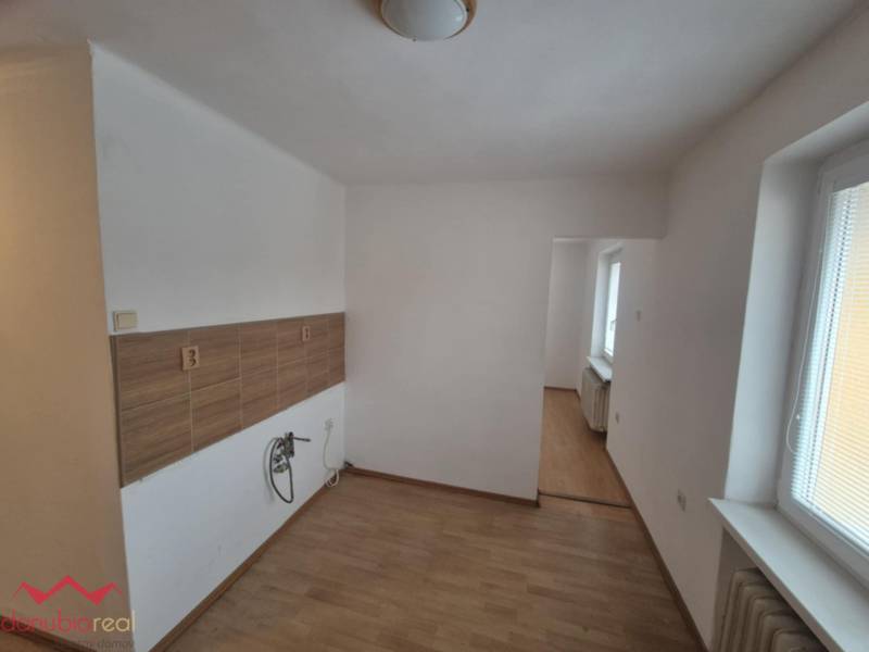 A kitchenette in a 2-room apartment with a wooden decor floor and a window.