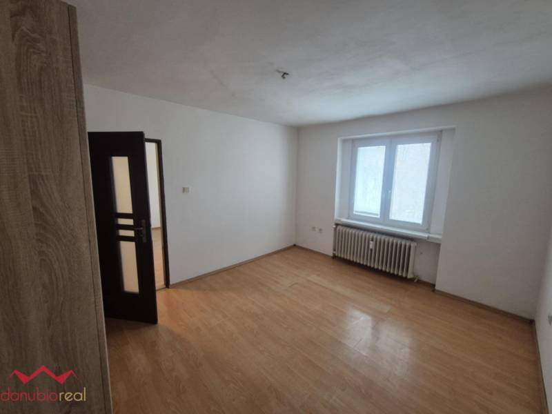A room in a 2-room apartment with a wooden decor floor and a radiator.