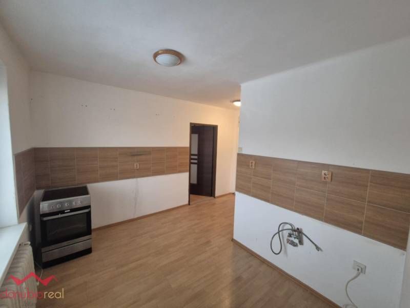 A kitchen in a 2-room apartment with a wood-patterned floor and a stove.