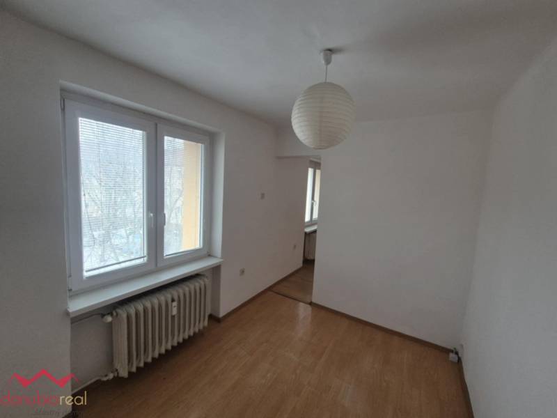 A room in a 2-room apartment with a wooden decor floor and a paper lamp.