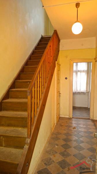 The interior of a family house with a wooden staircase and tiled floor.