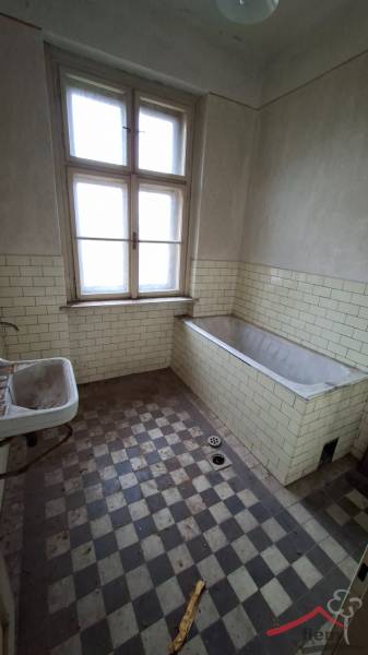 A bathroom in a family house with a bathtub and a tiled wall.