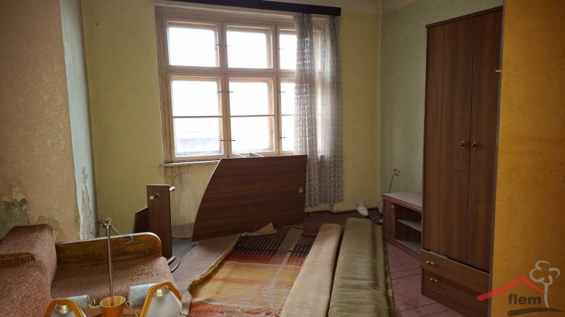 A room in a family house with old furniture and a window with transparent curtains.