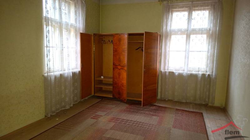 A room in a family house contains an older wardrobe and carpets with a delicate pattern.